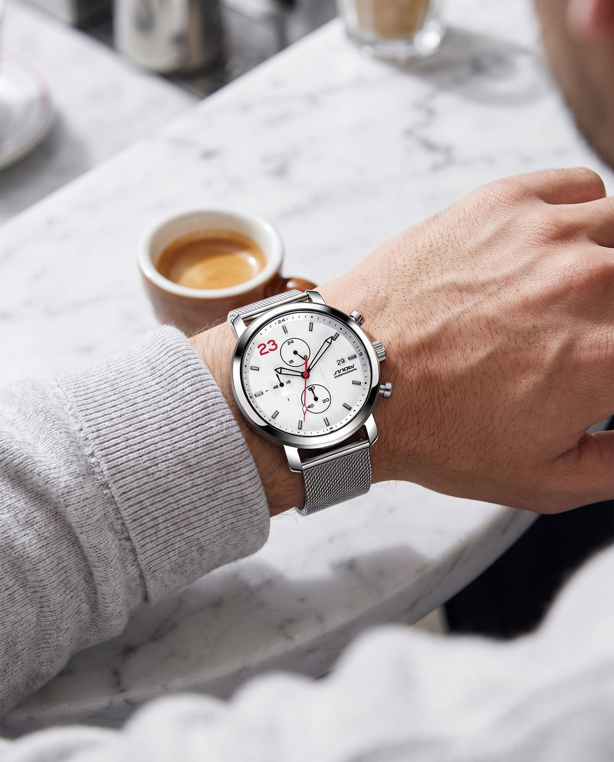 Man at cafe wearing SINOBI white chronograph with steel mesh bracelet