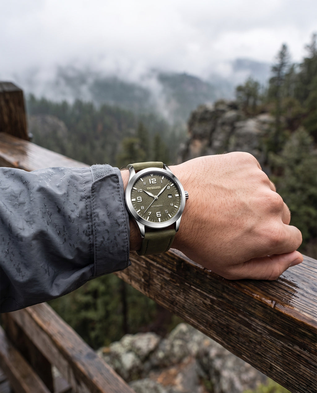 Man at mountain overlook wearing OCHSTIN green automatic watch