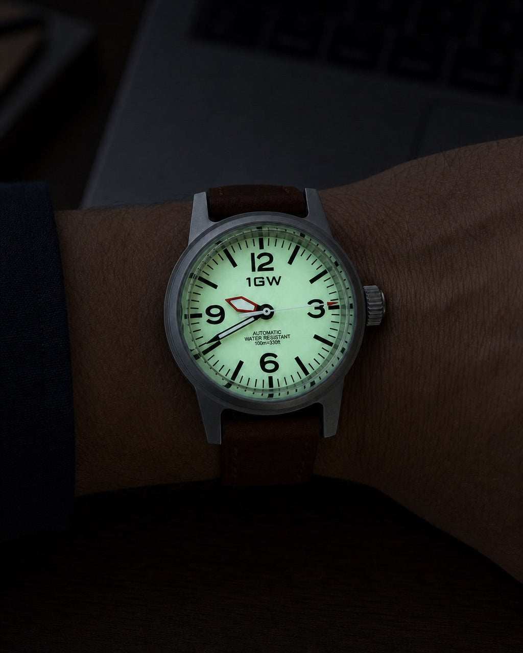 1GW Cream Field 36mm worn beside a keyboard with the full-lume dial glowing