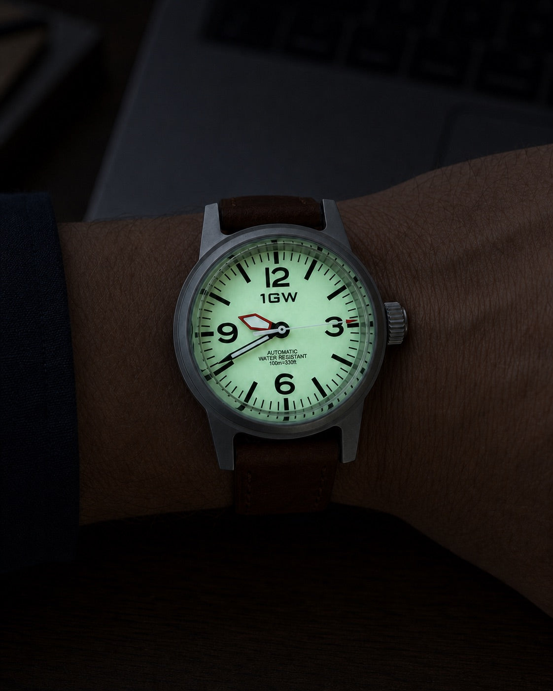 1GW Cream Field 36mm worn beside a keyboard with the full-lume dial glowing