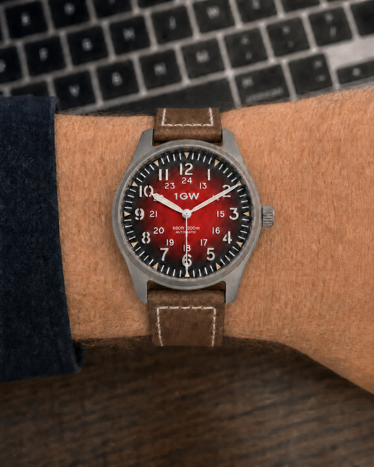 1GW Titanium Red GMT 36mm worn on the wrist beside a keyboard