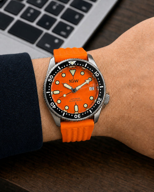 1GW Orange Diver 37mm on the outside of the wrist beside a laptop
