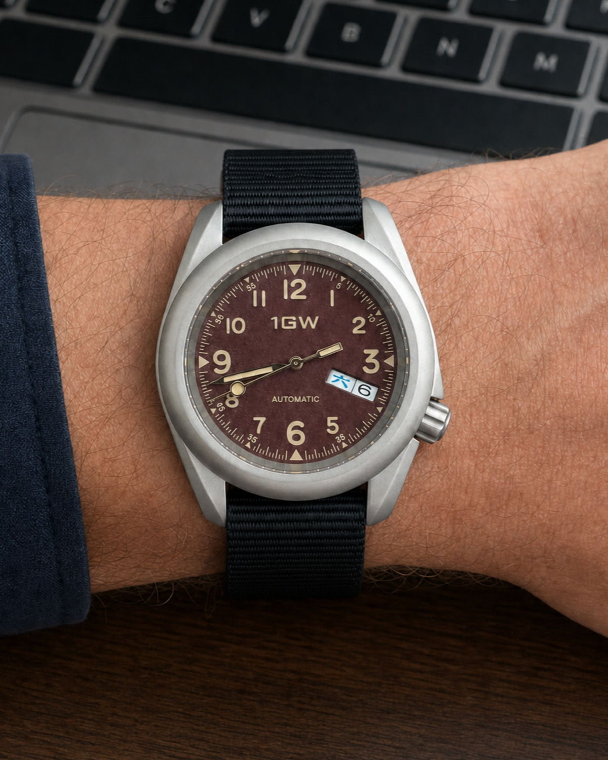 1GW Burgundy Field Day-Date on wrist beside a keyboard
