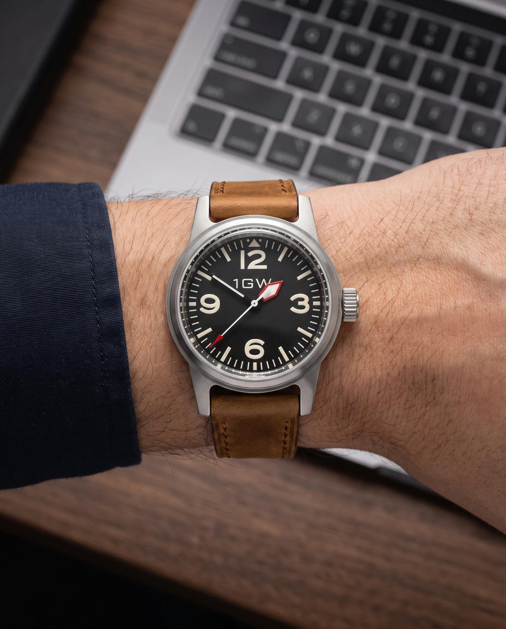 1GW Black Explorer NH35 36mm worn on the wrist beside a keyboard, tan leather strap