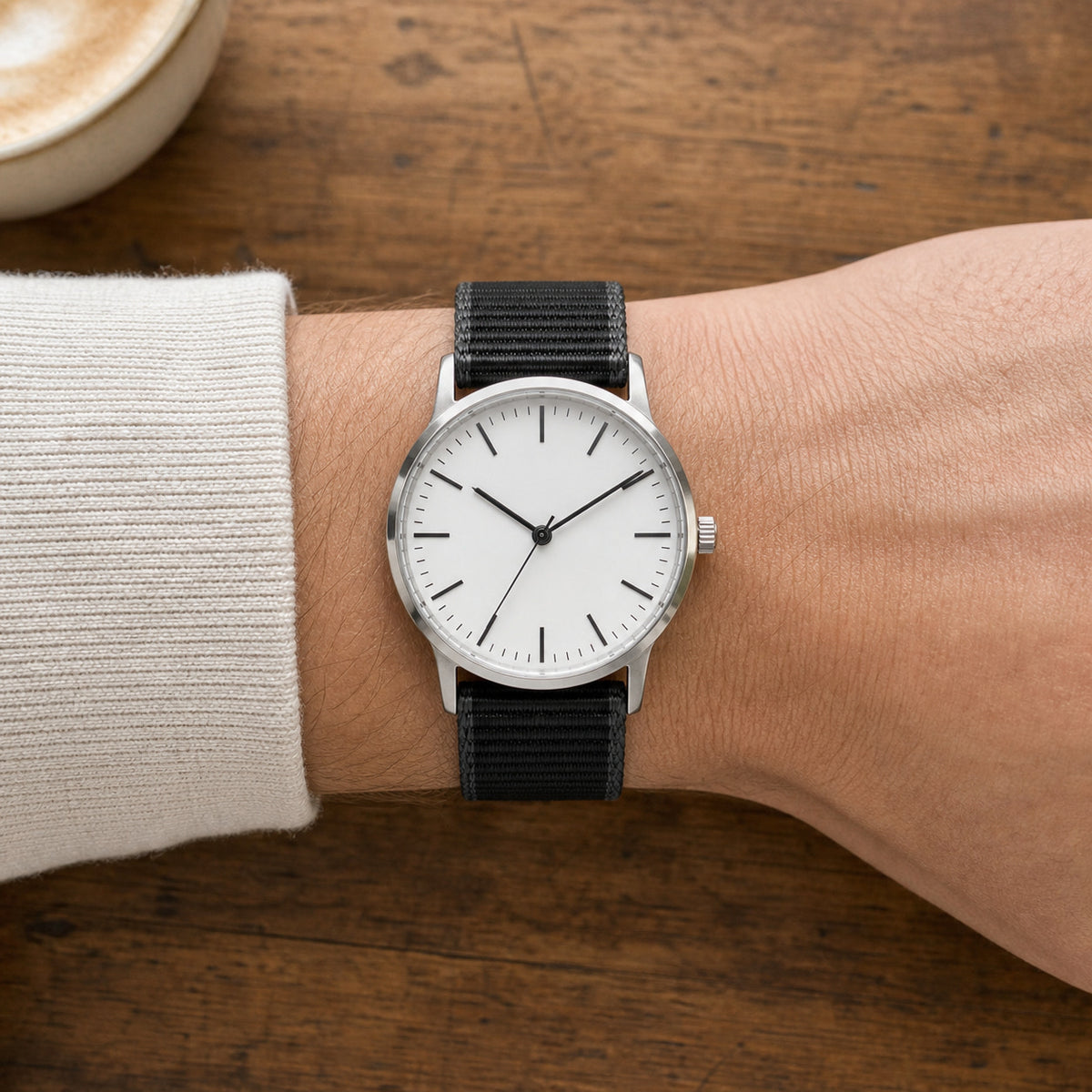 Black woven nylon quick-release watch strap worn in a top-down café view
