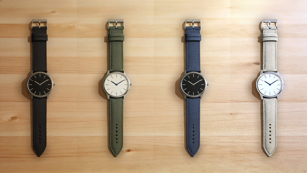 1GW Sailcloth quick-release watch strap in black, green, blue and beige, flat lay on wood