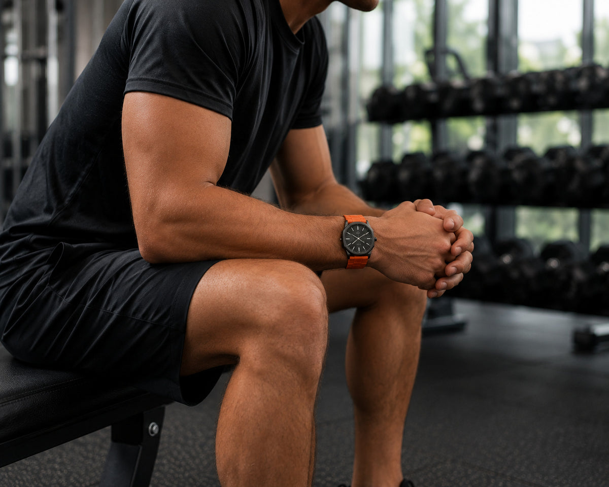 Orange silicone strap worn on a gym bench, One Good Watch lifestyle image