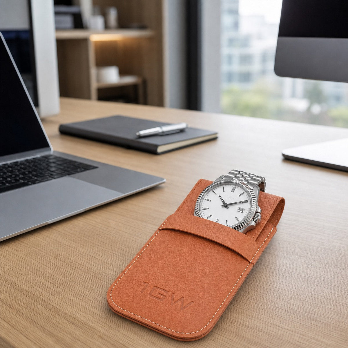 Tan 1GW watch travel pouch with white-dial watch on a modern office desk
