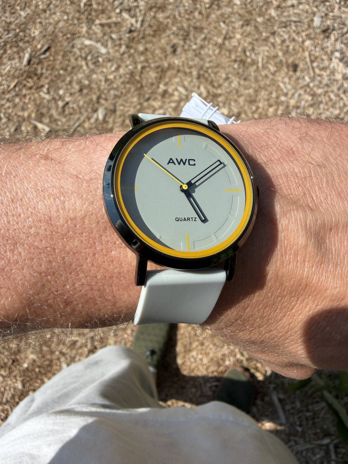 AWC Minimalist Quartz watch, grey dial with yellow ring and white silicone strap, worn on wrist outdoors