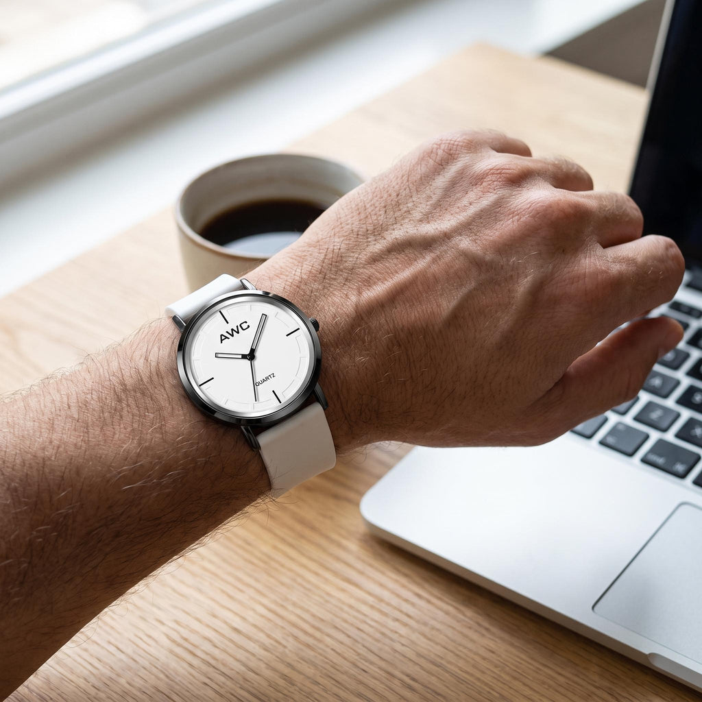 AWC Minimalist Quartz white dial watch worn on the wrist at a desk beside a laptop and coffee