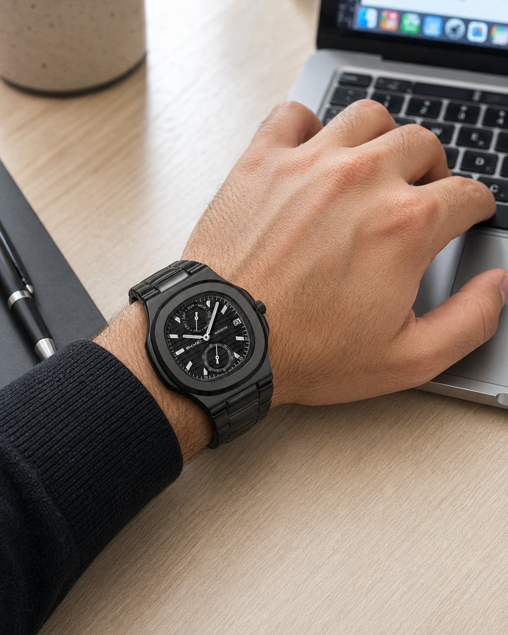 SKMEI 2423 black watch worn on the right wrist while using a laptop