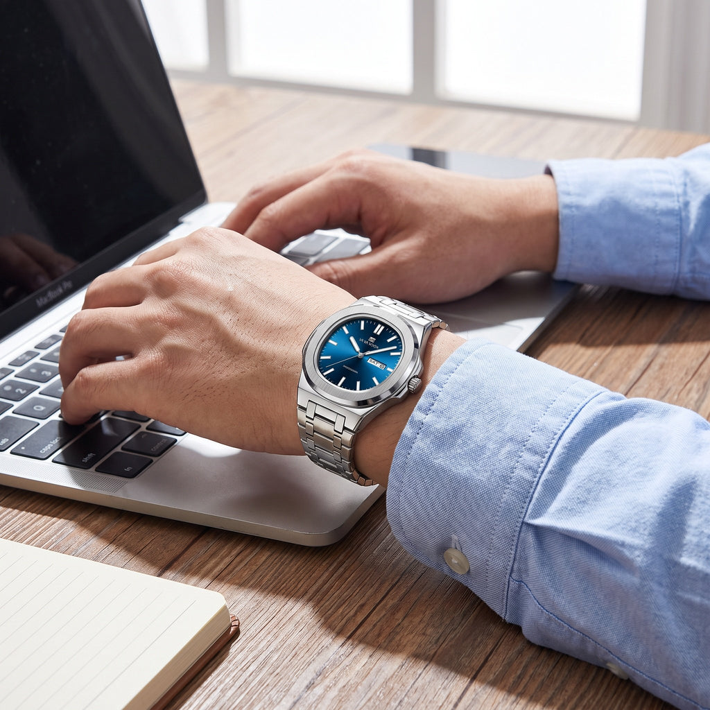 VA VA VOOM Octagonal Day-Date watch, steel with blue dial, worn on the wrist while typing at a laptop