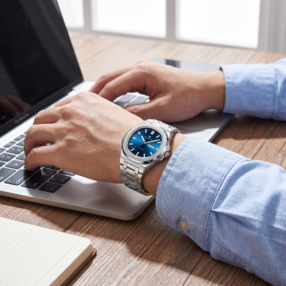 VA VA VOOM Octagonal Day-Date watch, steel with blue dial, worn on the wrist while typing at a laptop