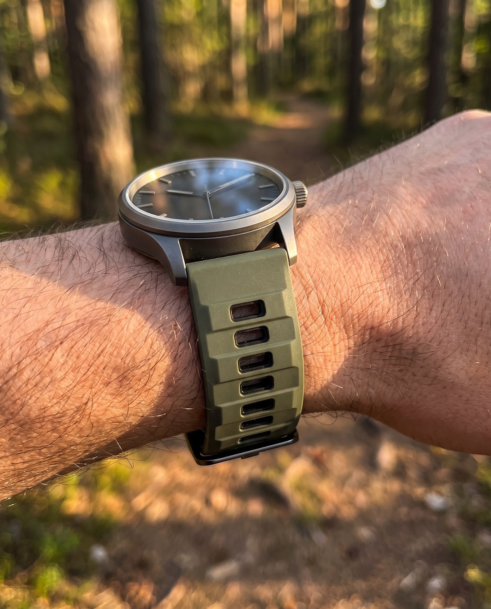 Army green and black two-tone silicone quick-release watch strap on a watch outdoors