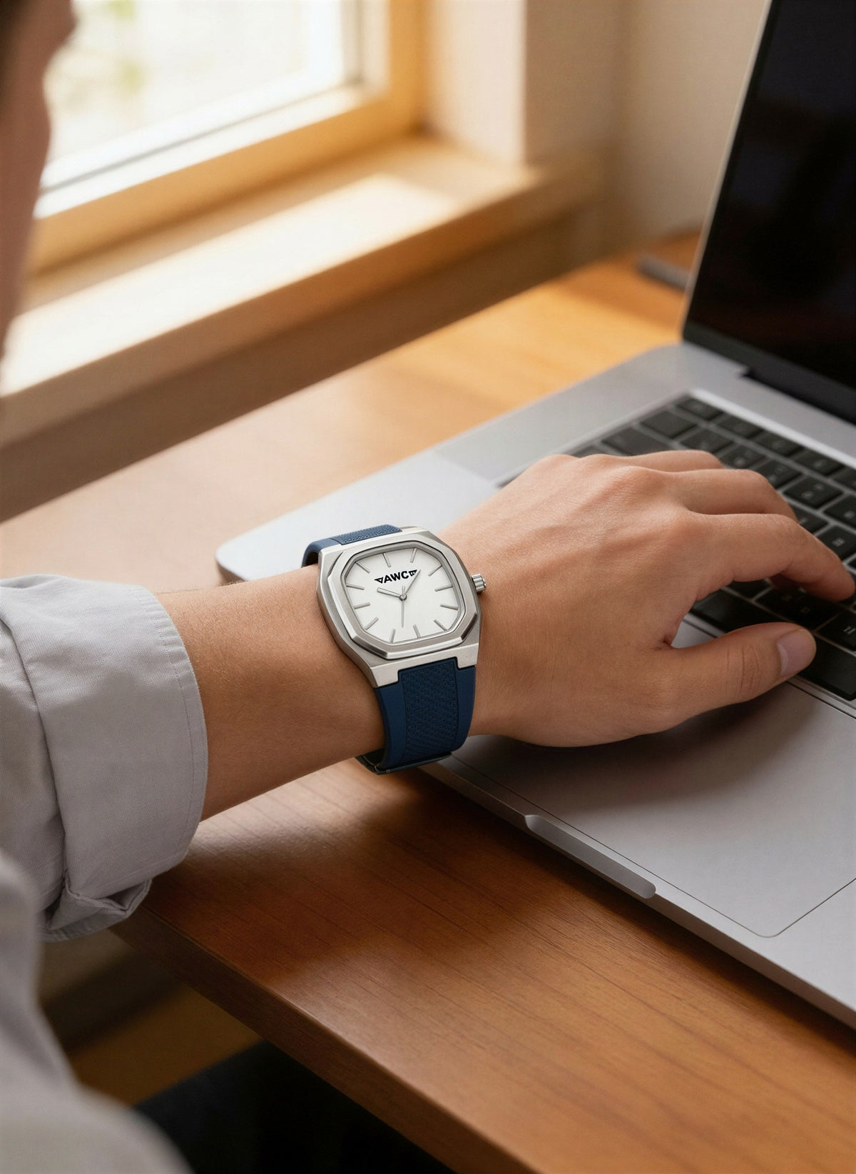AWC square quartz watch in blue worn while typing on a laptop