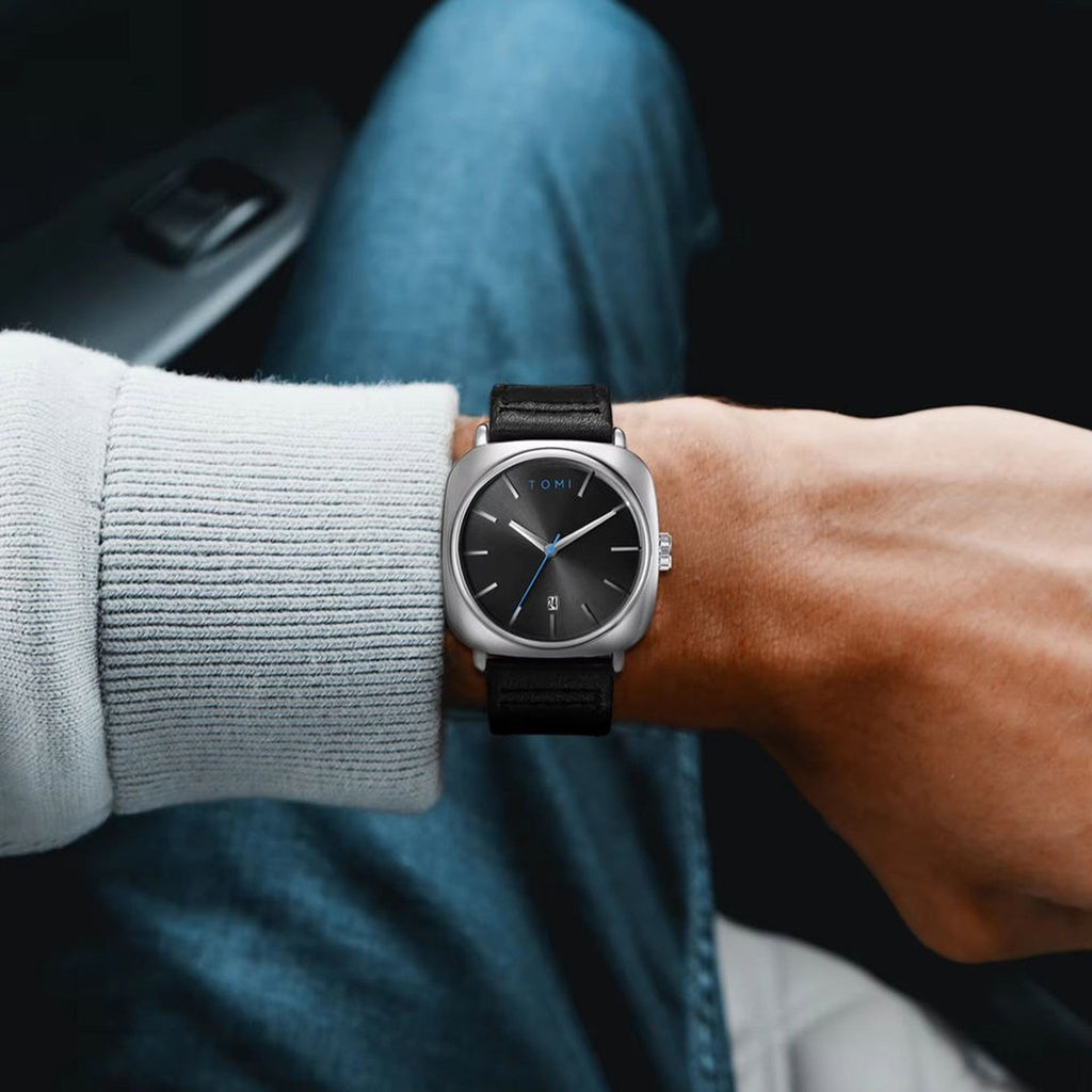 TOMI T084 silver case black dial quartz watch with black leather strap worn on wrist