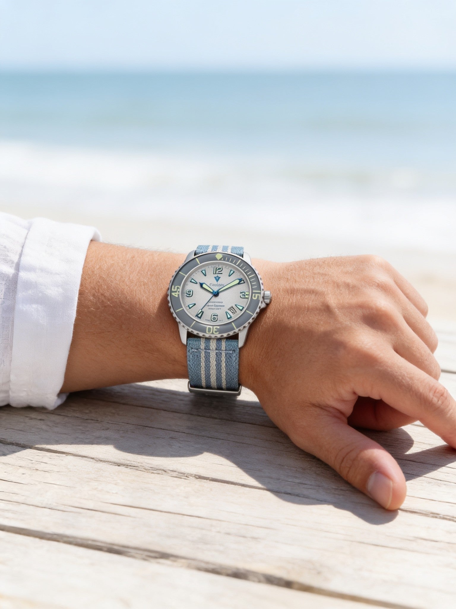 Steel 42mm automatic dive watch with white dial on wrist with light blue striped nylon strap