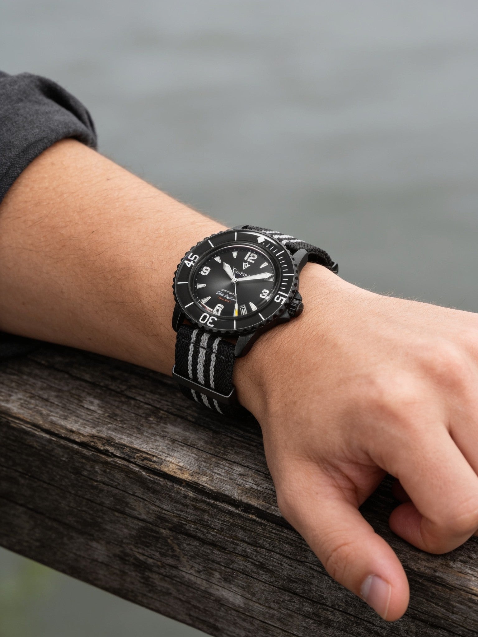 Black PVD 42mm automatic dive watch on wrist with black and grey striped nylon strap
