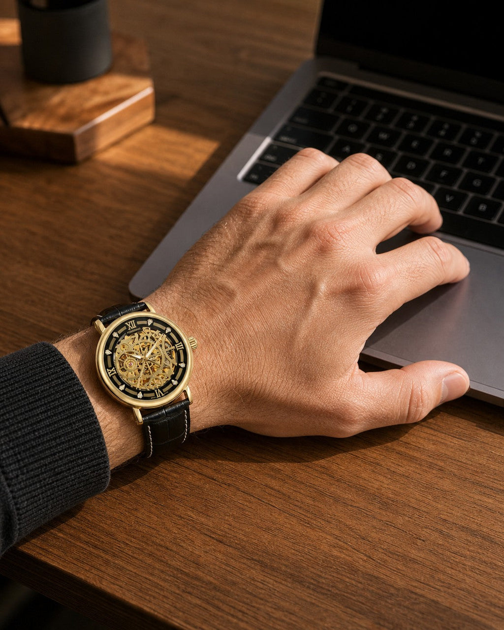 FORSINING Gold Black Leather skeleton mechanical watch worn at a laptop