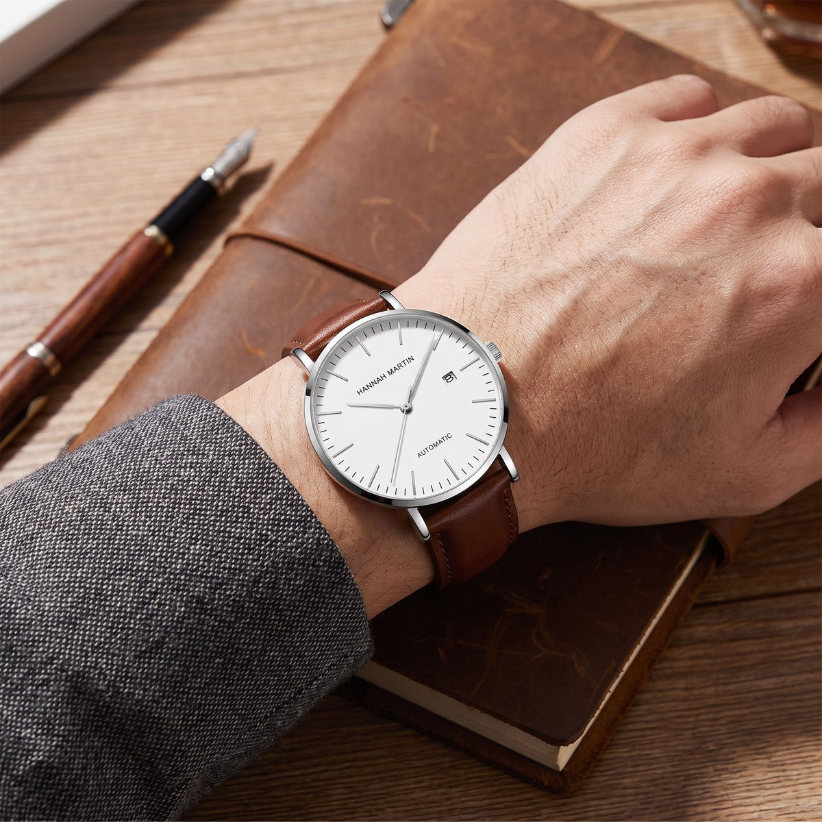 HANNAH MARTIN 1801 Automatic 41mm, white dial on brown leather, worn at a desk beside a leather notebook and pen