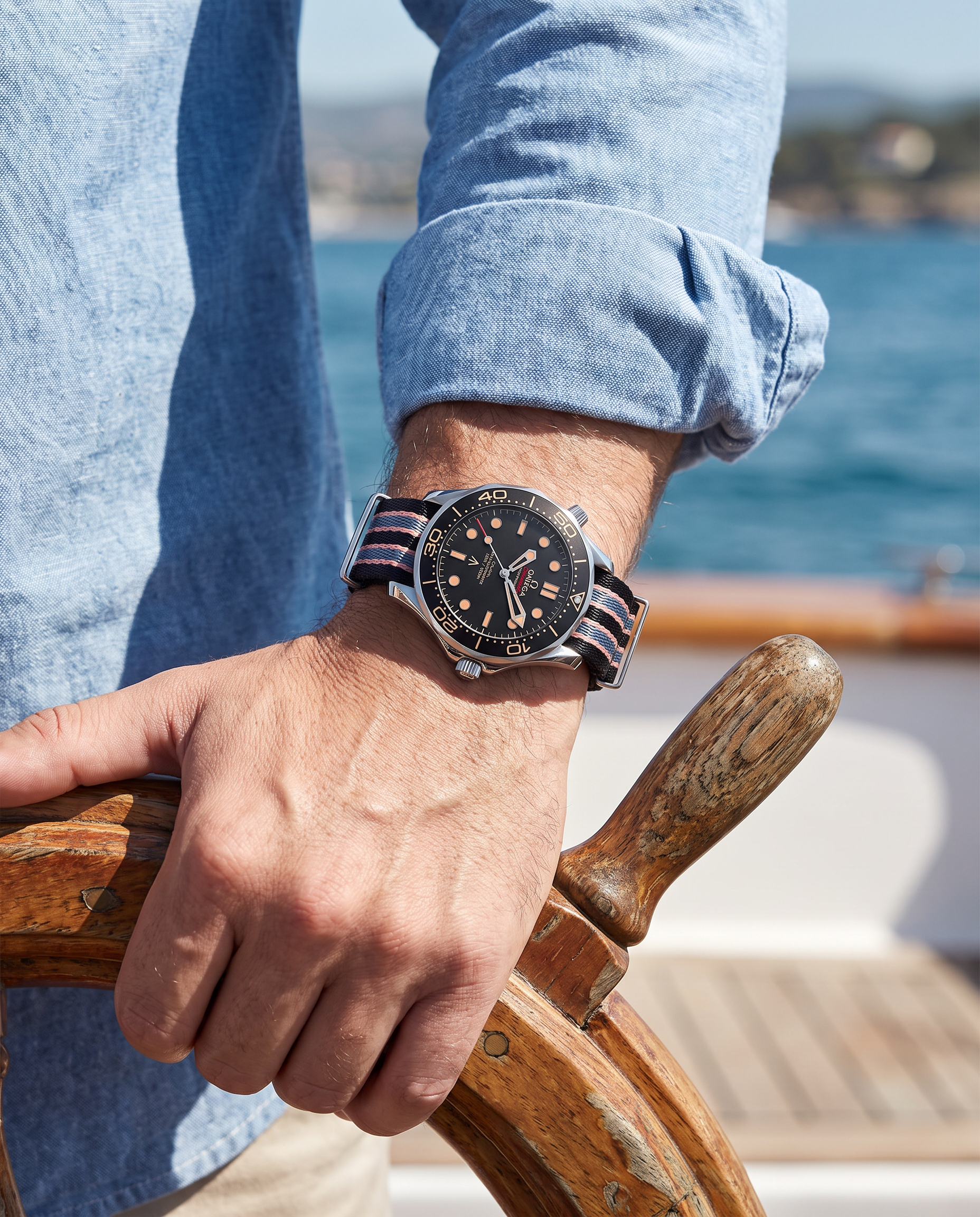 Man at boat wheel wearing Paulareis dive watch with striped NATO strap