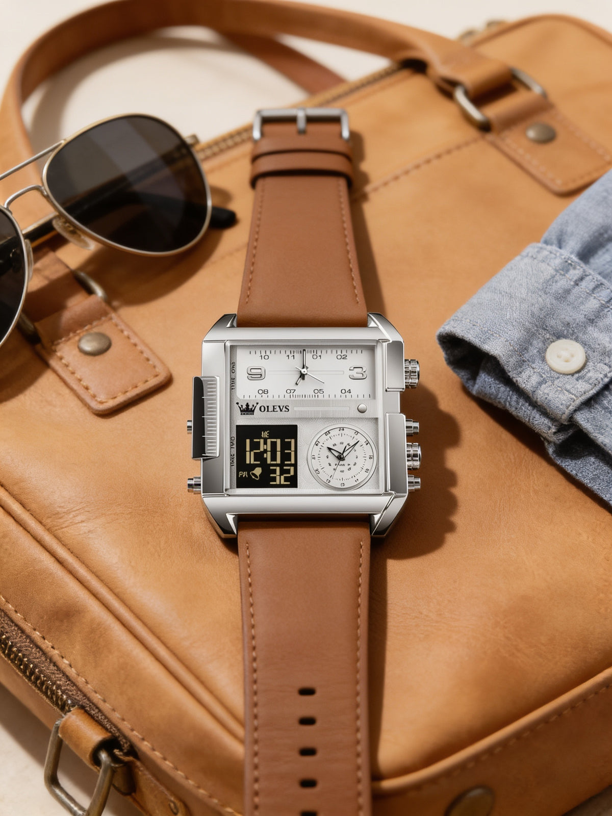 OLEVS silver and brown leather analog-digital watch flat-lay on a tan leather weekender bag
