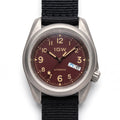 1GW Burgundy Field Day-Date Titanium 40mm - straight-on studio hero on white, burgundy textured dial, cream numerals, day-date at 3
