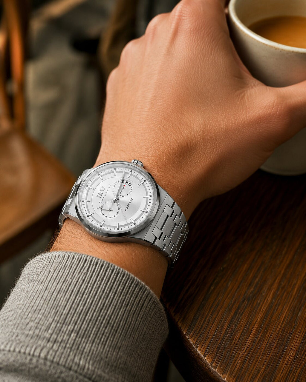 Man wearing Carnival IW55870G white dial automatic watch with steel bracelet at a café