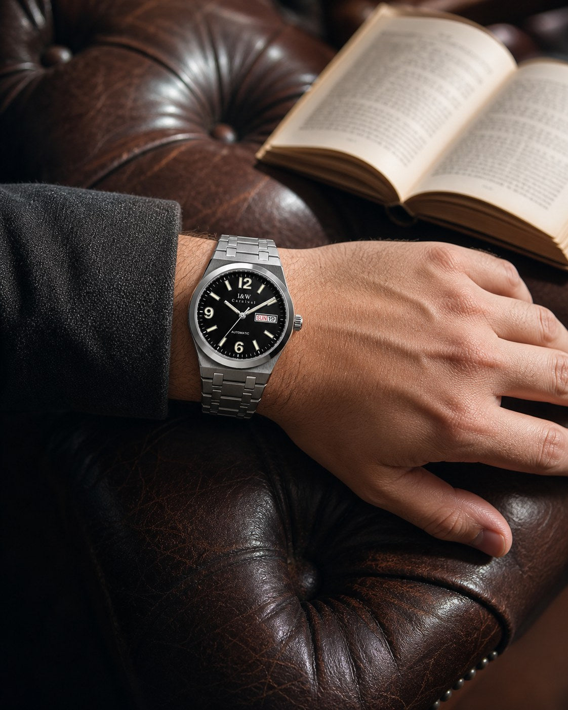 Carnival black day-date automatic watch on wrist beside a book and leather chair