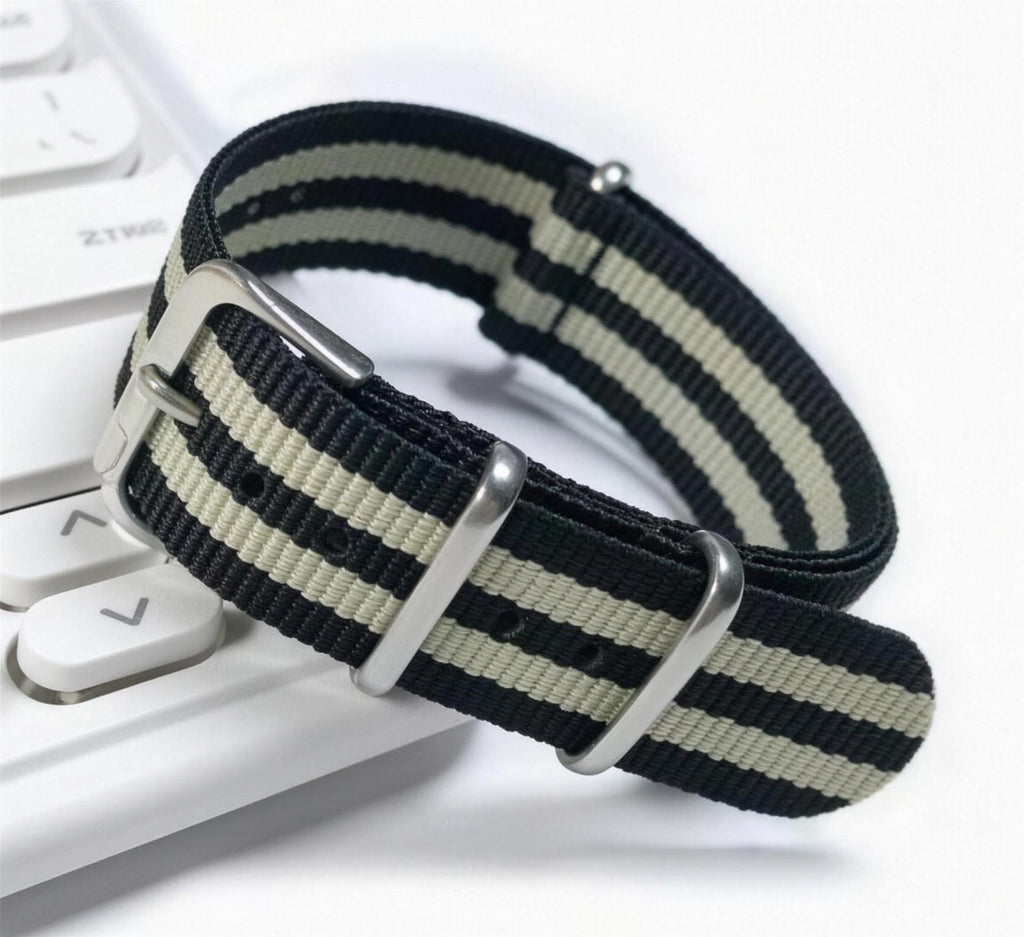 Black and gray striped woven nylon pass-through watch strap, coiled to show the weave