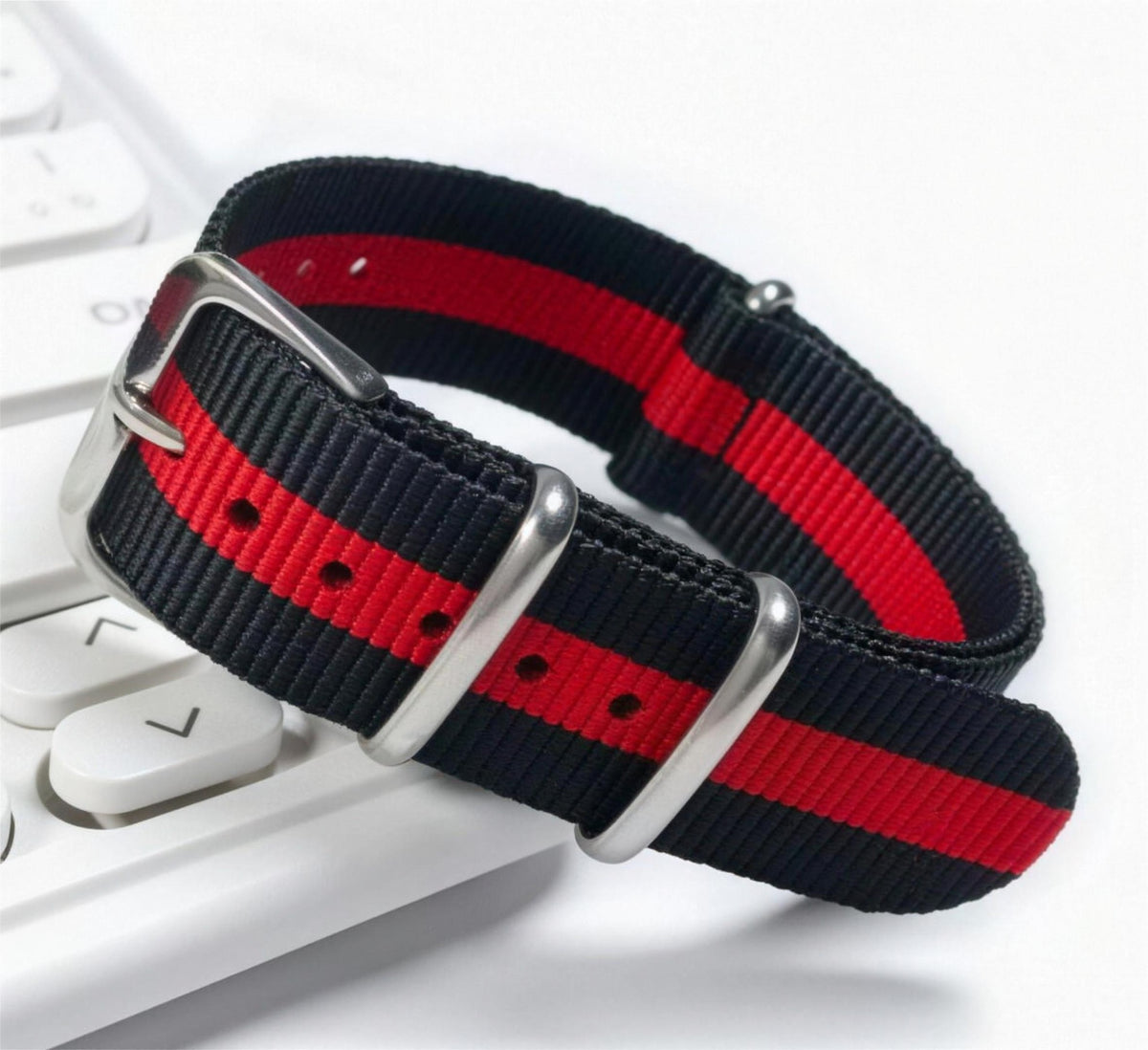 Black and red striped woven nylon pass-through watch strap, coiled to show the weave