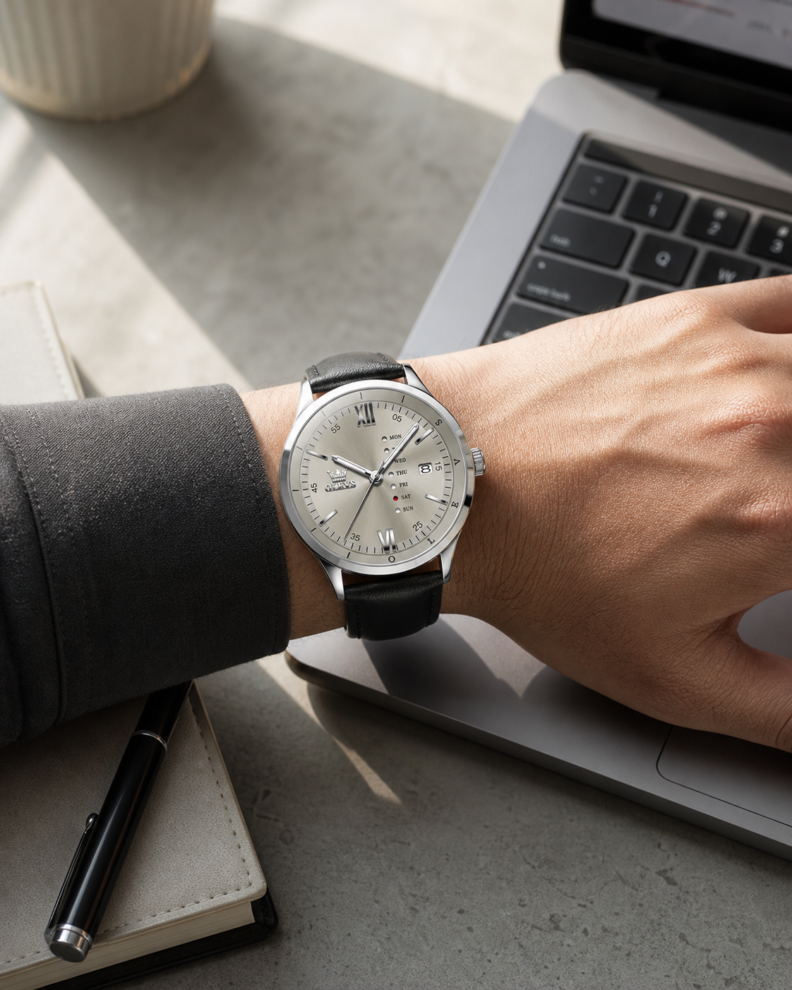 OLEVS Gray day-date watch worn at a laptop