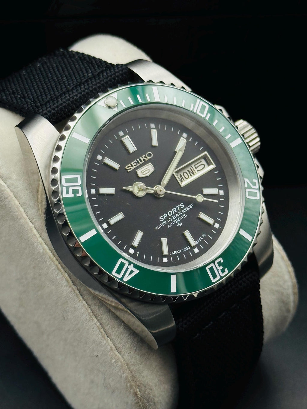 Green-bezel Seiko automatic watch showing stainless-steel sports case