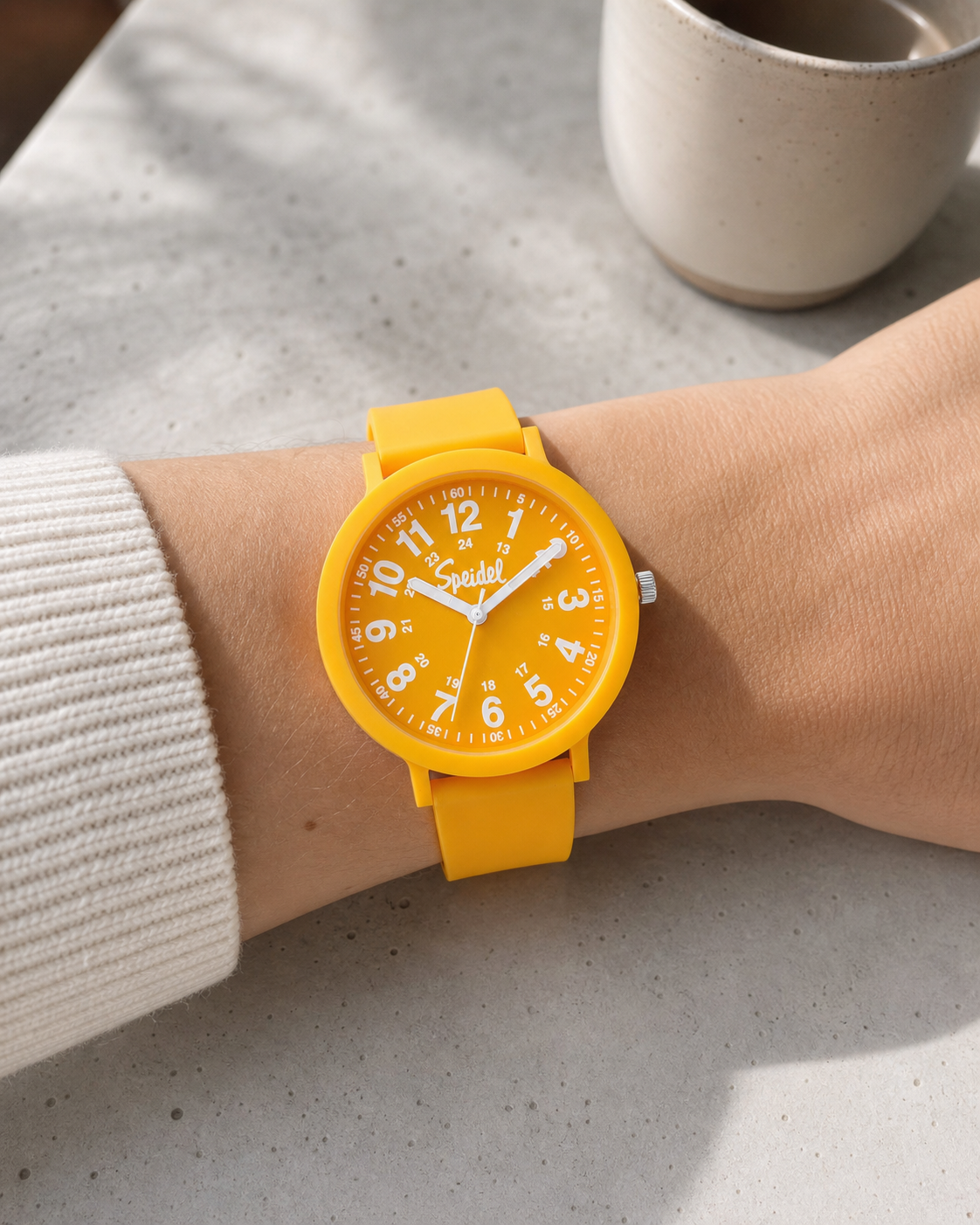 Speidel Eco Color Pop Mimosa watch worn at a café table