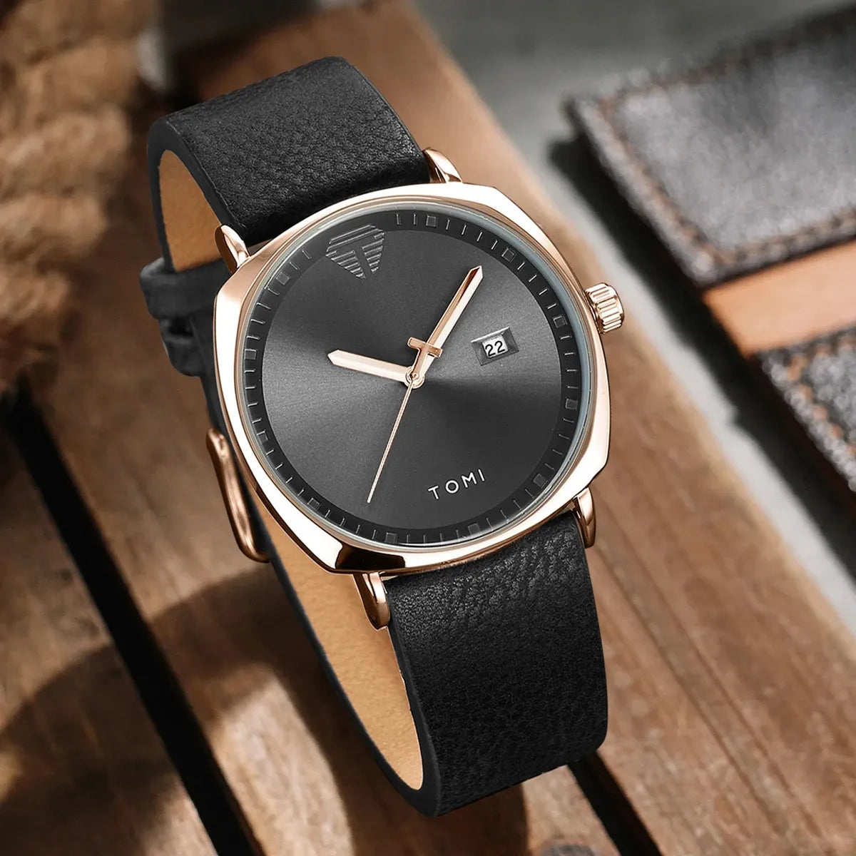 TOMI minimalist calendar quartz watch with gold case, black dial, and black leather strap