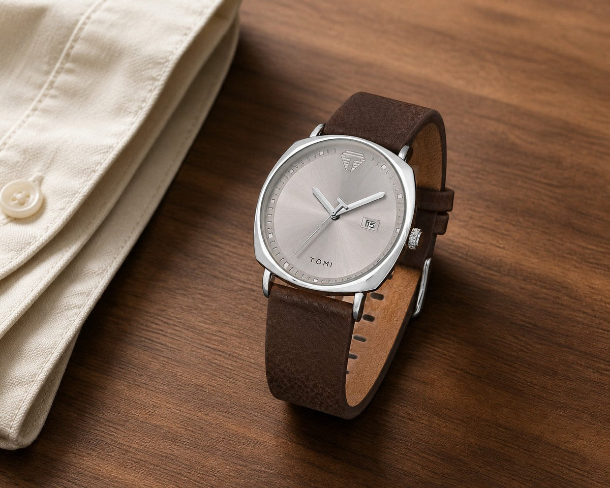 TOMI silver dial and silver case quartz watch with brown leather strap on a walnut desk